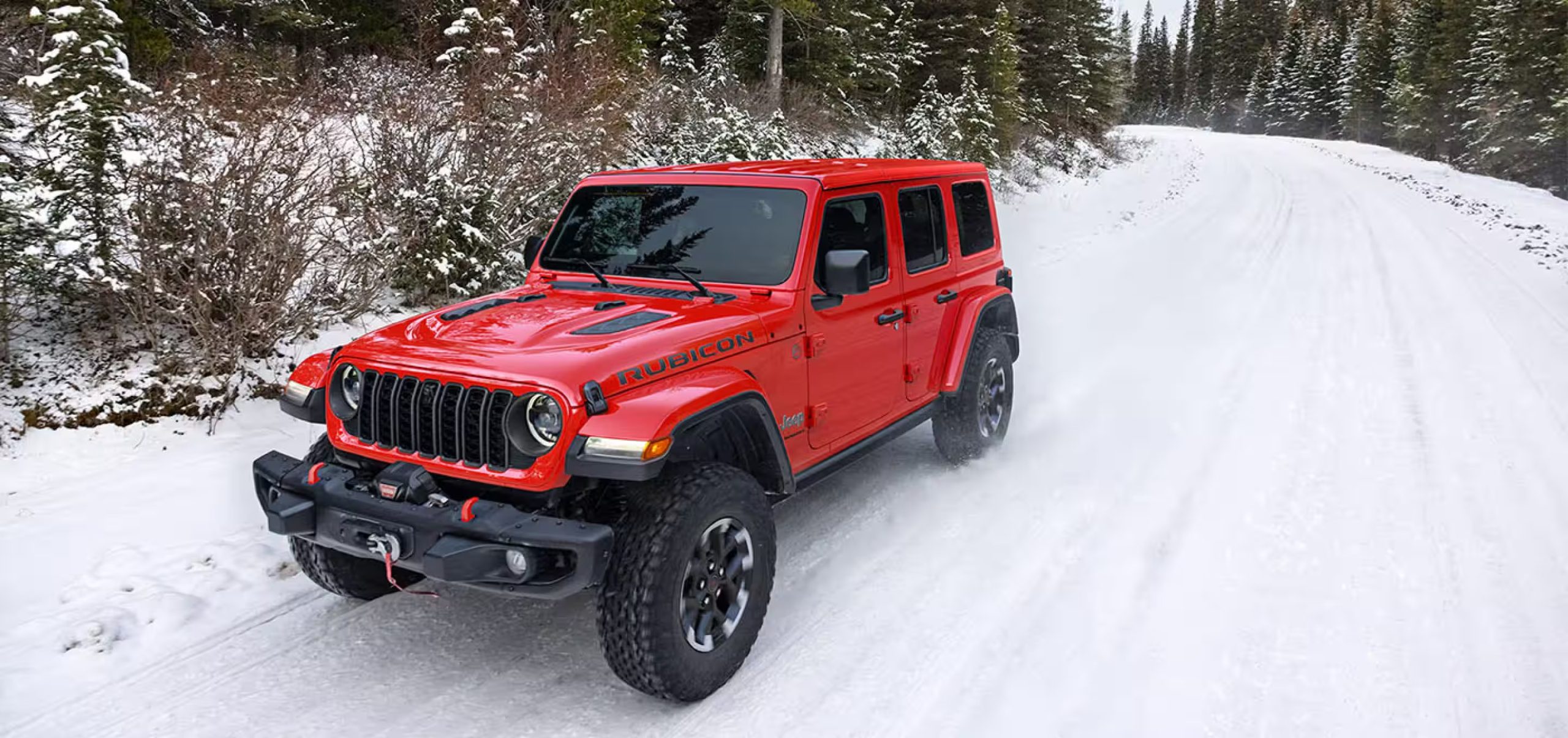 A red 2026 Jeep Wrangler driving through snow