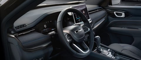 A person is shown interacting with a smartphone to connect to a Jeep vehicle across the street. | Bachrodt Baraboo Motors in Baraboo WI